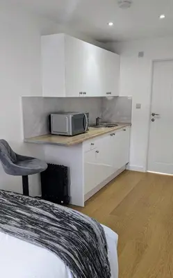 a kitchen with a microwave on a counter next to a bed at The Southend Airport Lodge in Southend-on-Sea