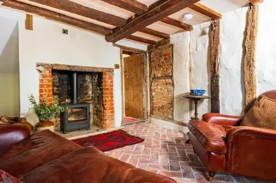 a living room with a couch and a fireplace at Taper House - Cosy Medieval Cottage in Kersey