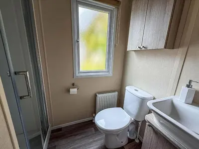 a bathroom with a toilet and a sink and a window at Stunning Caravan At West Mersea Park 75192Wm in West Mersea