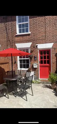 a table and two chairs with a red umbrella at Cottage of Content in Wivenhoe