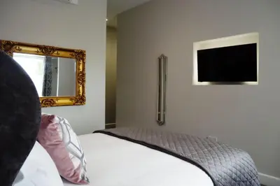a bedroom with a bed with a mirror and a television at Thomas Paine Hotel in Thetford