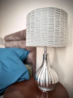 a glass lamp sitting on a table next to a bed at Churchgate Apartment in Bury Saint Edmunds