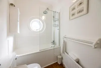 a white bathroom with a shower and a toilet at La Ronessa, Aldeburgh in Aldeburgh