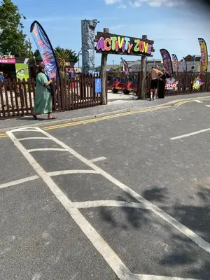 a woman standing in a parking lot next to a fence at Hadleigh Caravans at Seawick Clacton in Clacton-on-Sea