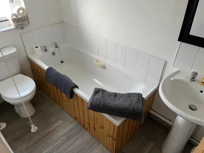 a bathroom with a tub and a toilet and a sink at Harleston Norfolk Suffolk border Historic Cottage in Harleston