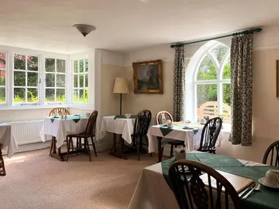 a dining room with two tables and a window at Little rooms at The Cottage in Bishops Stortford