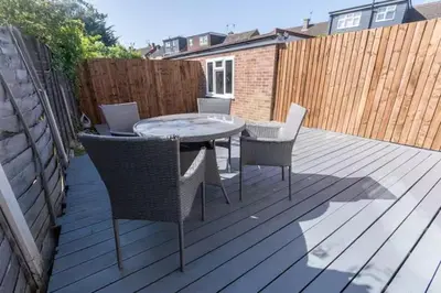 a patio with a table and chairs on a wooden deck at Stylish and comfortable 4-Bedroom Retreat in the Heart of Chelmsford in Chelmsford