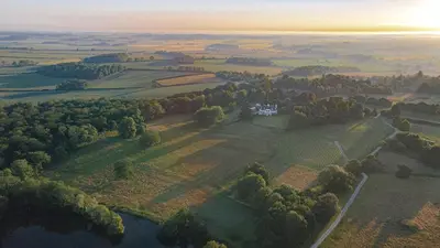 an aerial view of a house on a hill next to a lake at The Flat - Waresley Park Estate