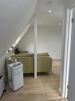 a living room with a couch and a staircase at A Lovely and Cosy Studio Apartment in Navestock