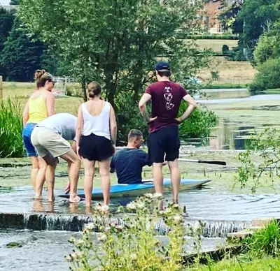 a group of people standing on a surfboard in the water at Stables 2bed farm stay private firepit bbq in Bramfield