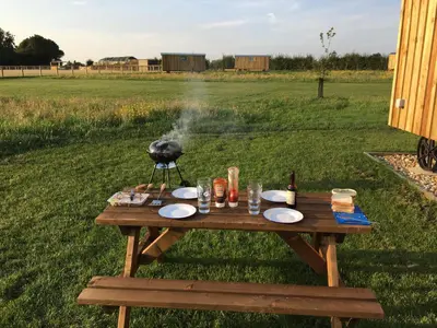 a bird standing on a picnic table in a field at Shepherds Hut 5 in Woodbridge