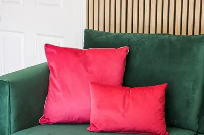 a green couch with two red pillows on it at Stylish 2 Bedroom Property in Bury Saint Edmunds