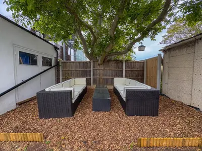 a patio with two couches sitting under a tree at Seafront Beach House in Southend-on-Sea