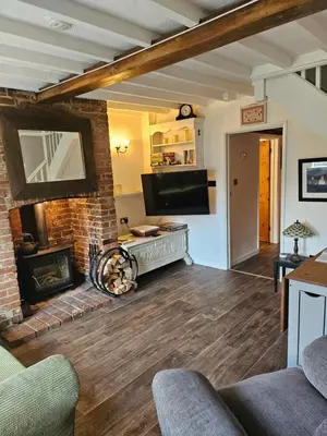 a living room with a fireplace and a tv at 2 Church Path in Earsham