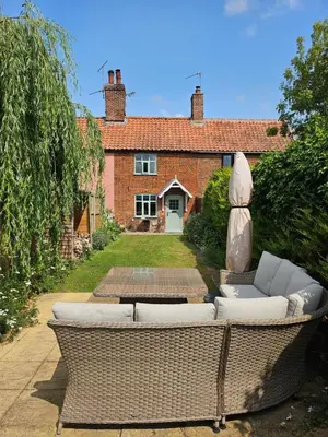 a garden with two wicker furniture in front of a house at 2 Church Path in Earsham