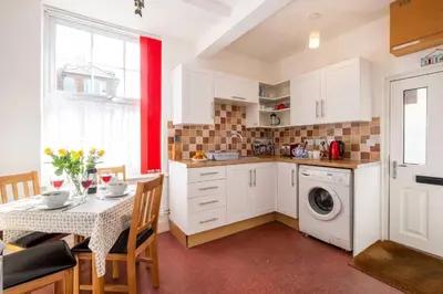 a kitchen with a table and a washing machine at Pebbles, King St - Aldeburgh Coastal Cottages in Aldeburgh