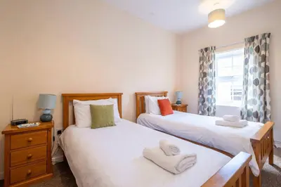 a bedroom with two beds and a window at Pebbles, King St - Aldeburgh Coastal Cottages in Aldeburgh