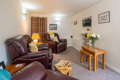 a living room with leather furniture and a tv at Pebbles, King St - Aldeburgh Coastal Cottages in Aldeburgh