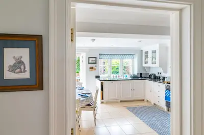 a kitchen with white cabinets and a table at Samphire in Aldeburgh