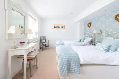 two beds in a room with a table and a desk at Samphire in Aldeburgh