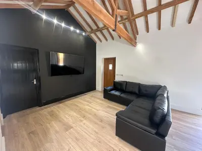 a living room with a black couch and a flat screen tv at The Old stables Barn in Old Hurst