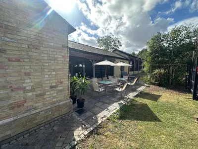 a patio with a table and chairs and umbrellas at The Old stables Barn in Old Hurst