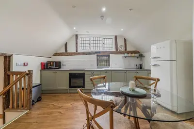a kitchen with a glass table and a refrigerator at Luces Loft in Castle Hedingham