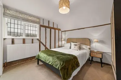a bedroom with a large bed and two windows at Luces Loft in Castle Hedingham