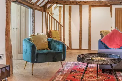 a living room with a blue chair and a table at Luces Loft in Castle Hedingham