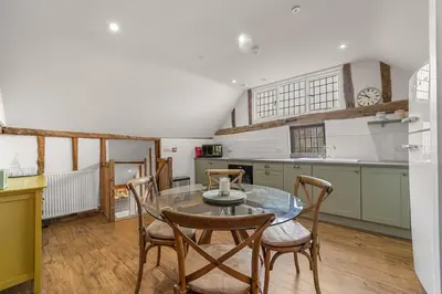 a kitchen with a glass table and chairs at Luces Loft in Castle Hedingham