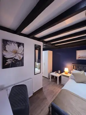a bedroom with a bed and a chair in a room at The Courtyard Lodge in Hitchin