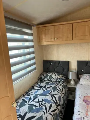 a small bedroom with a bed and a window at Rohannah A&C Ultimate Caravan Retreat in East Mersea