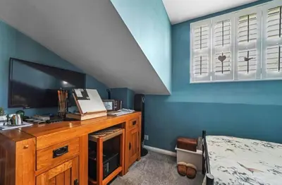 a bedroom with a bed and a desk with a television at A Beautiful Country Cottage in Waldringfield