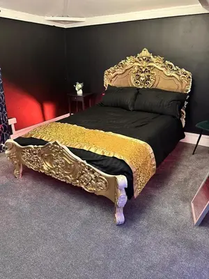 a bedroom with a bed with a black and gold at Essex Dungeon Suite in Heybridge