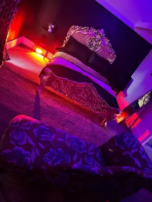 a bedroom with two beds with purple and red lights at Essex Dungeon Suite in Heybridge