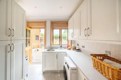 a kitchen with white cabinets and a sink at Large indoor swimming pool in Thetford Forest - The Pool House in Downham