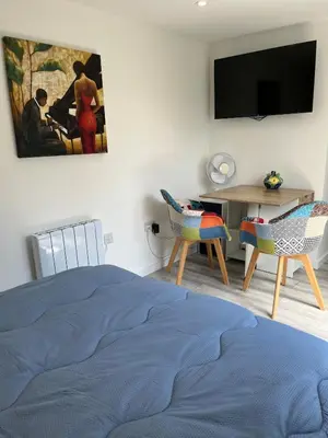 a bedroom with a bed and a desk with chairs at Dolly Studio in Colchester