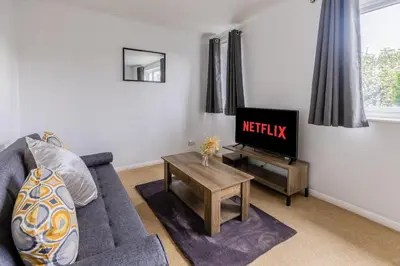 a living room with a couch and a tv at Cambridge House near Addenbrookes, station and parking! in Shelford