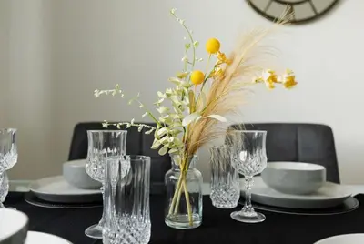 a table with glasses and a vase with flowers in it at Cambridge House near Addenbrookes, station and parking! in Shelford