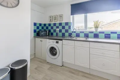 a kitchen with a washing machine and a sink at Cambridge House near Addenbrookes, station and parking! in Shelford