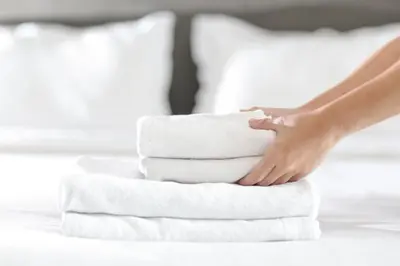 a woman is stacking towels on a bed at Stylish 2 bed apartment - easy walk to Addenbrookes in Cambridge