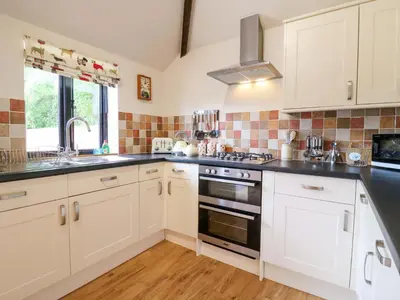 a kitchen with white cabinets and a sink and a stove at The Golden Cross in Harleston