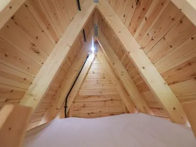 a room in a wooden attic with a ladder at Robin in Woodbridge