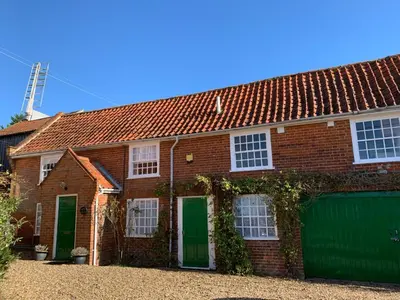 a brick house with green doors and a garage at The Coach House, Framsden