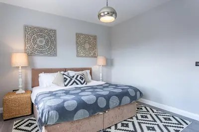 a bedroom with a bed with a blue and white comforter at 2BR Apartments in Southend near City Centre in Southend-on-Sea
