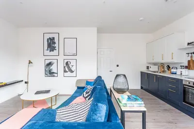 a living room with a blue couch and a table at 2BR Apartments in Southend near City Centre in Southend-on-Sea