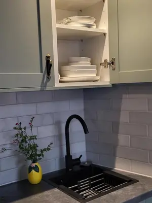 a kitchen counter with a sink and a cupboard with plates at Cozy Studio Newly Furnished in Colchester