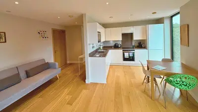 a living room and kitchen with a couch and a table at Modern Central Apartment with Parking in Cambridge