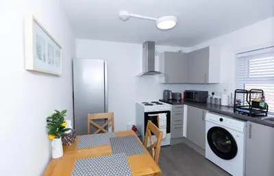 a kitchen with a table and a refrigerator at Urban Escape - Flat in Brandon