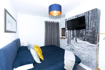 a bedroom with a blue bed and a flat screen tv at Urban Escape - Flat in Brandon